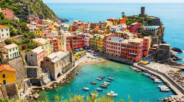 Veduta panoramica di un colorato borgo sul mare con barche ormeggiate e edifici storici