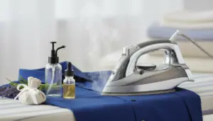 Ferro da stiro a vapore su camicia blu con flaconi di essenze profumate