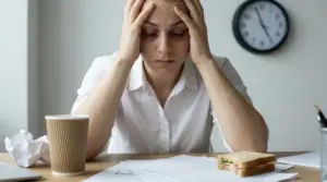 Persona seduta alla scrivania con le mani sulla testa in un gesto di stress