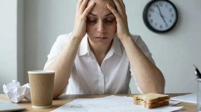 Persona seduta alla scrivania con le mani sulla testa in un gesto di stress