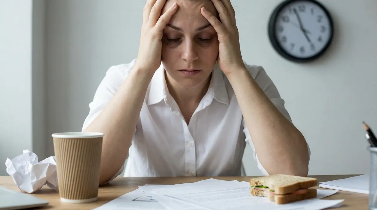 Persona seduta alla scrivania con le mani sulla testa in un gesto di stress