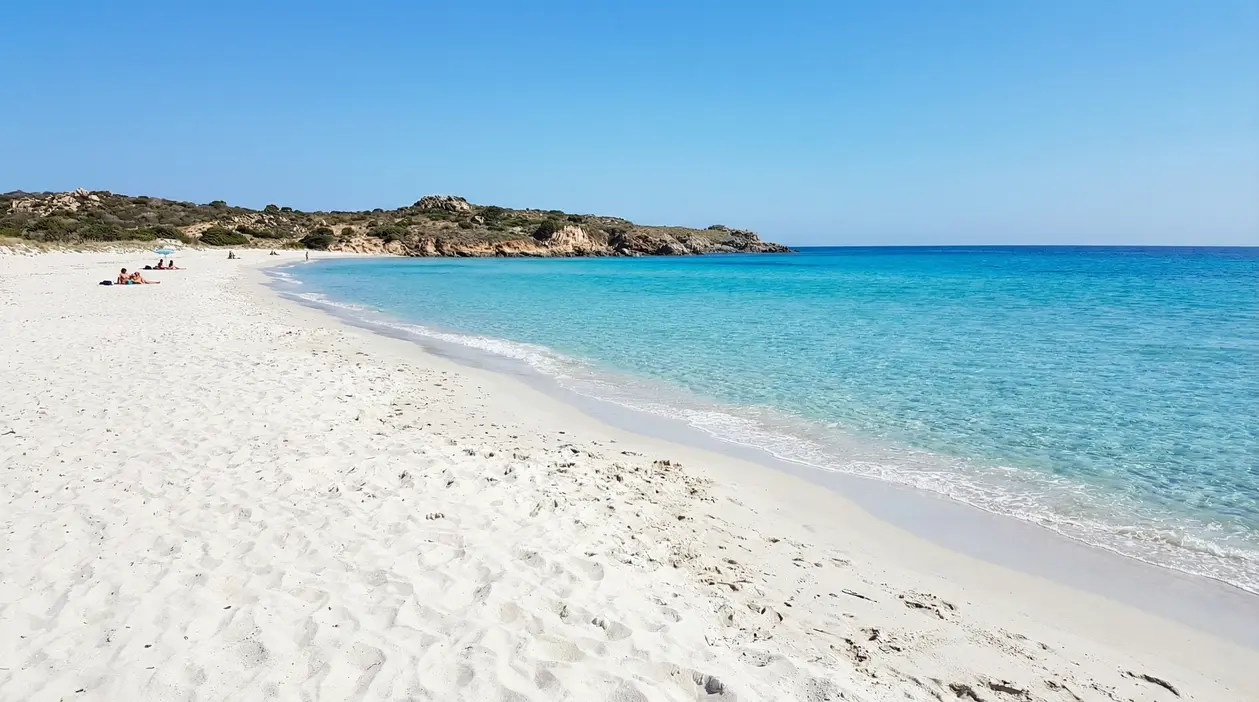 Spiaggia con sabbia bianca e mare cristallino in una baia tranquilla